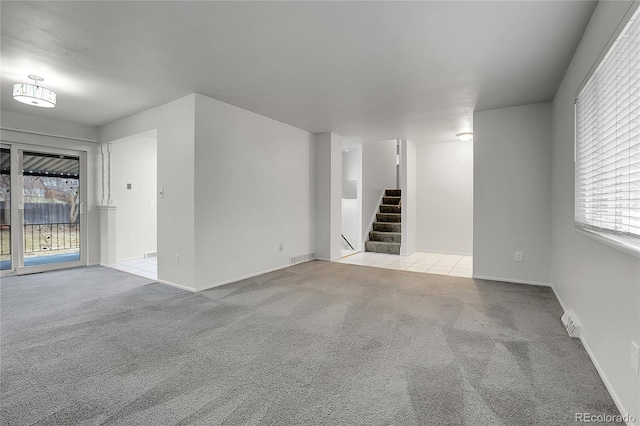 carpeted empty room with visible vents, stairway, and baseboards