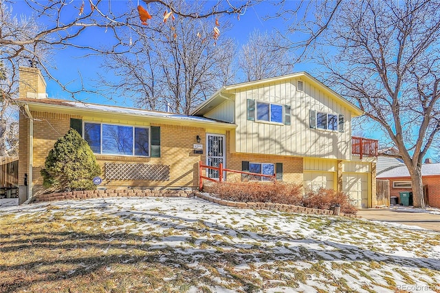 tri-level home featuring driveway, brick siding, and a chimney