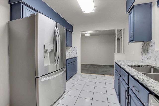 kitchen featuring light carpet, stainless steel fridge with ice dispenser, blue cabinetry, backsplash, and light stone countertops