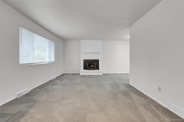 unfurnished living room featuring carpet, a fireplace, visible vents, and baseboards