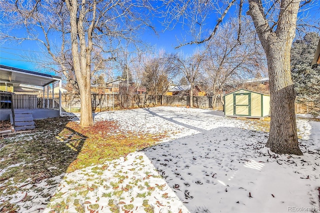 yard layered in snow with an outbuilding, a shed, and a fenced backyard