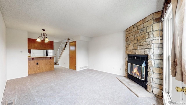 6796 S Independence St, Littleton, CO 80128 - unfurnished living room featuring a textured ceiling, a stone fireplace, stairs, light carpet, and a chandelier
