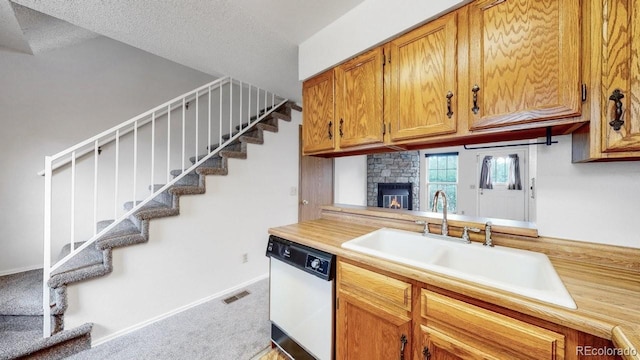 6796 S Independence St, Littleton, CO 80128 - kitchen with dishwasher, light countertops, brown cabinetry, carpet, and a stone fireplace