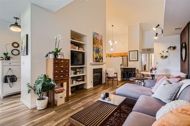 living room with wood-type flooring, built in features, and a high ceiling