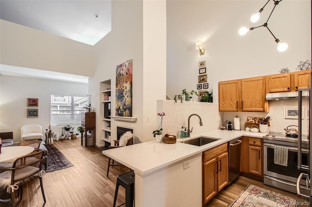 kitchen with a high ceiling, stainless steel appliances, sink, backsplash, and kitchen peninsula