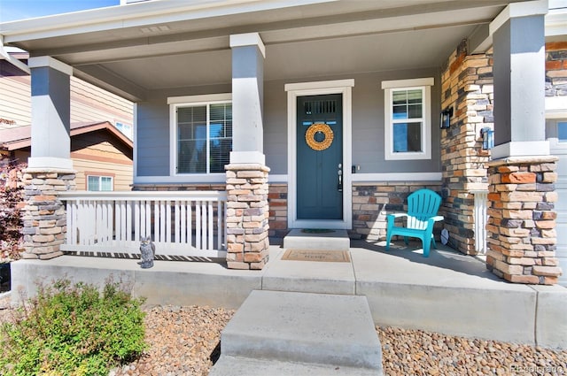 entrance to property with covered porch and stone siding