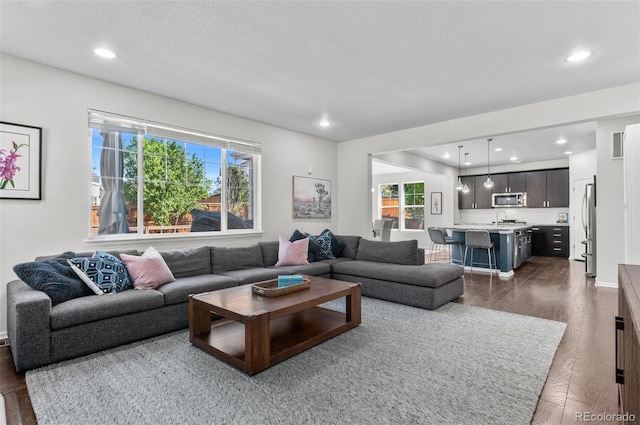 living area featuring dark wood-type flooring and recessed lighting