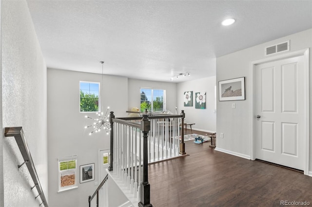 stairway featuring wood finished floors, baseboards, a textured ceiling, and a chandelier