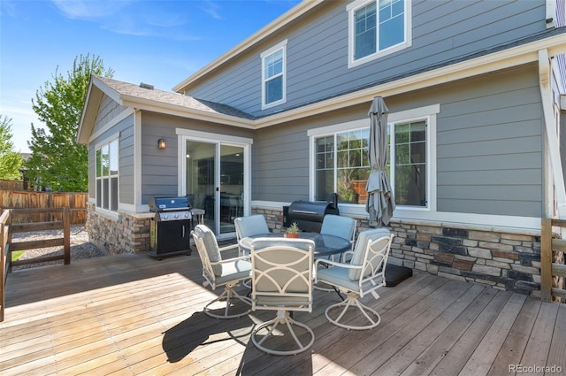 wooden deck with area for grilling, outdoor dining area, and fence