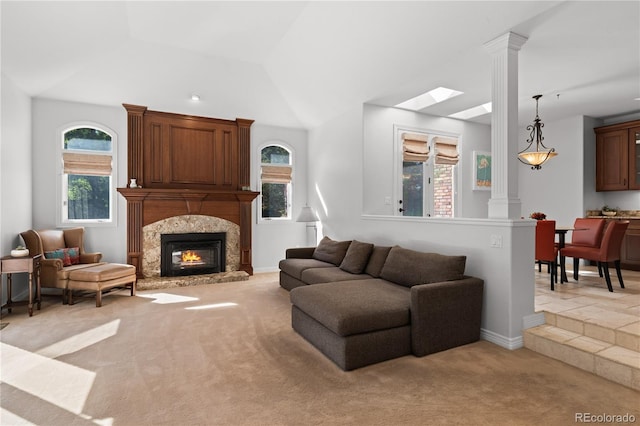 carpeted living room with lofted ceiling, a large fireplace, and ornate columns