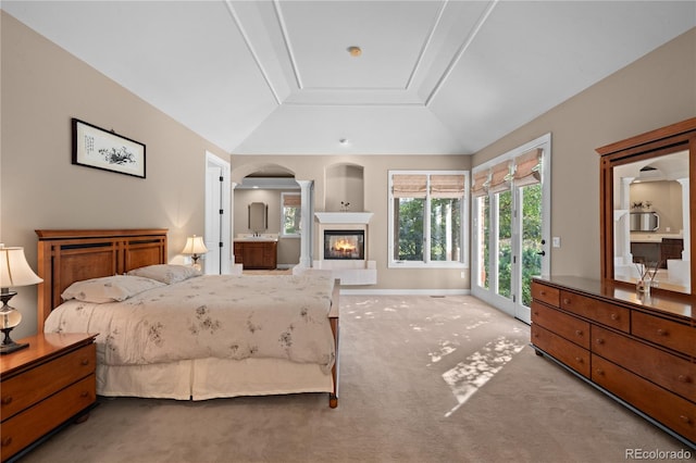 bedroom with light colored carpet, lofted ceiling, access to exterior, and a tiled fireplace