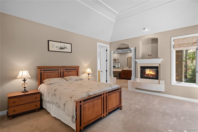 bedroom featuring lofted ceiling, ensuite bath, light colored carpet, and a multi sided fireplace