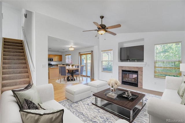 9905 Aftonwood St, Highlands Ranch, CO 80126 - living area with vaulted ceiling, stairs, ceiling fan, a tile fireplace, and light wood-type flooring