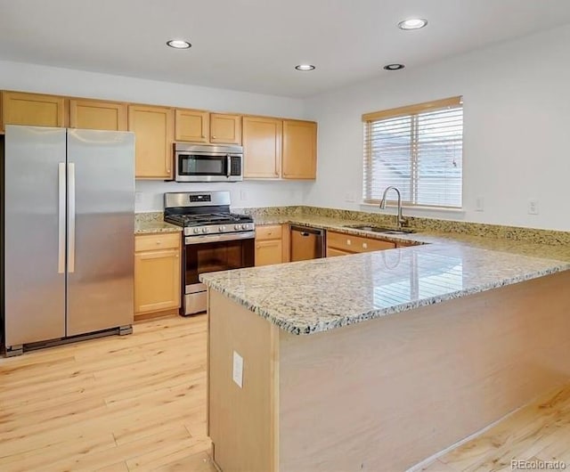 9905 Aftonwood St, Highlands Ranch, CO 80126 - kitchen featuring appliances with stainless steel finishes, light brown cabinetry, a peninsula, light wood finished floors, and light stone countertops
