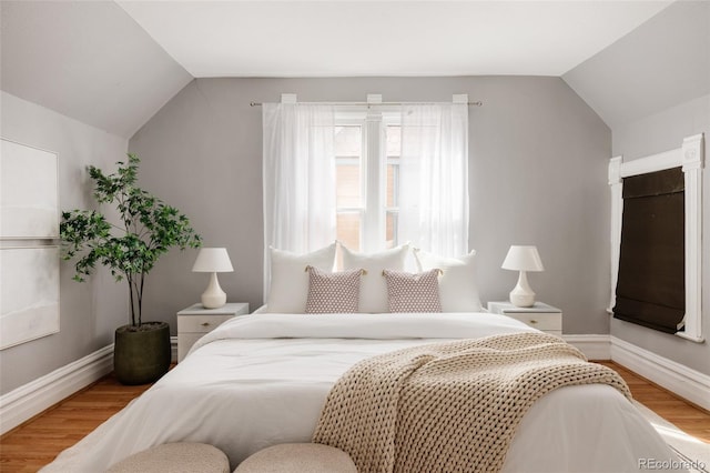 bedroom with baseboards, vaulted ceiling, and wood finished floors
