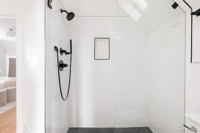 bathroom with wood finished floors and a tile shower