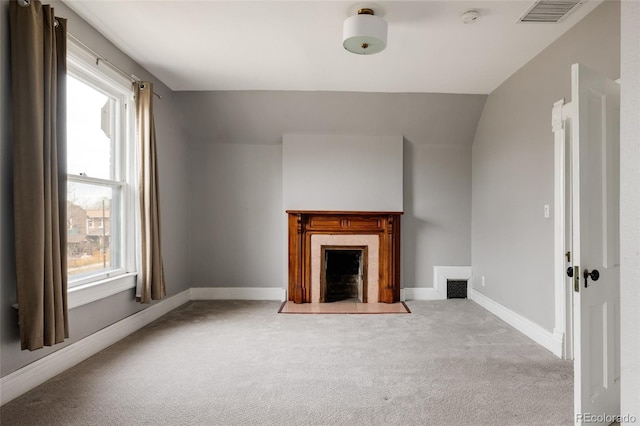 unfurnished living room featuring carpet flooring, a premium fireplace, baseboards, and visible vents