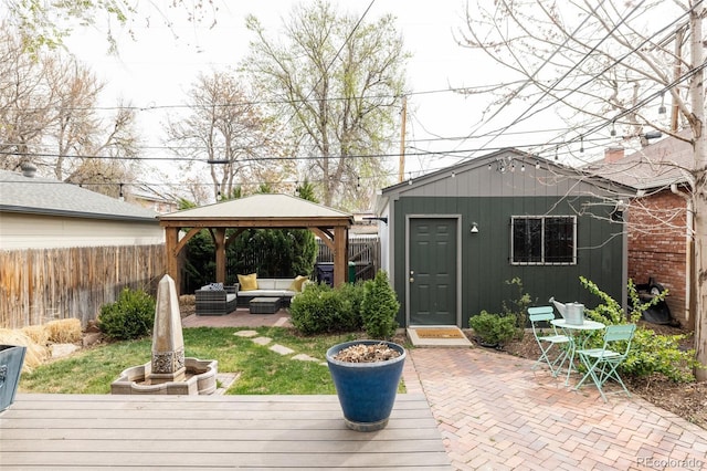 view of outdoor structure with an outdoor living space, a fenced backyard, and a gazebo
