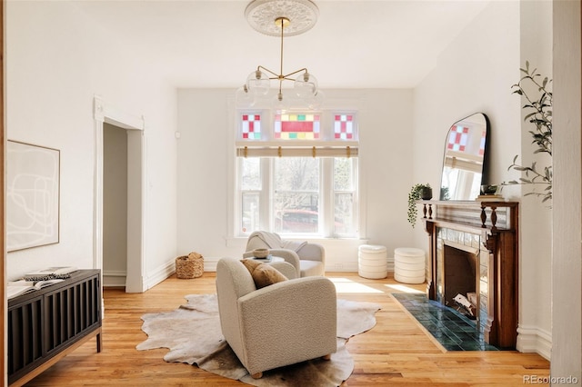 living room featuring radiator heating unit, wood finished floors, a tile fireplace, baseboards, and an inviting chandelier