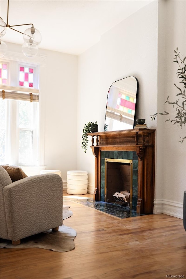 living room featuring baseboards, an inviting chandelier, wood finished floors, and a fireplace