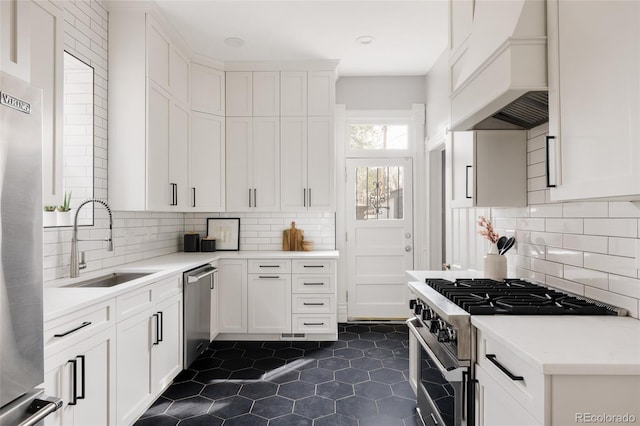 kitchen with appliances with stainless steel finishes, decorative backsplash, a sink, and custom range hood