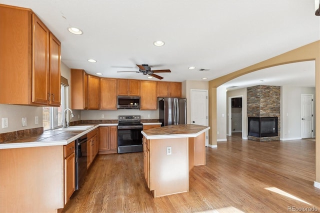 16351 E 104th Pl, Commerce City, CO 80022 - kitchen featuring black appliances, a sink, a kitchen island, open floor plan, and light wood finished floors