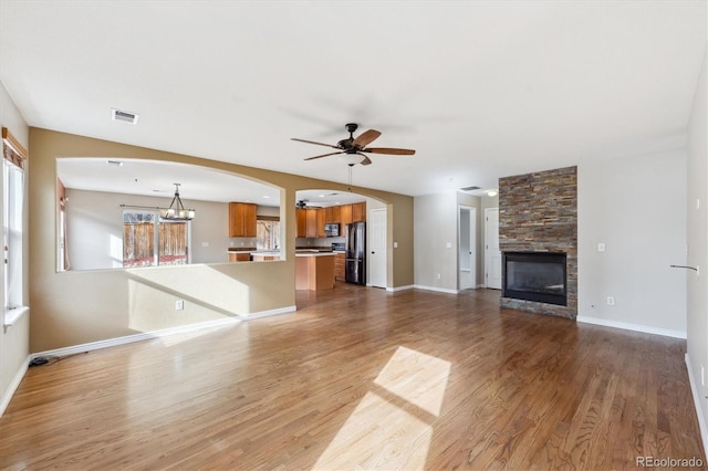 16351 E 104th Pl, Commerce City, CO 80022 - unfurnished living room featuring ceiling fan, light wood-style floors, arched walkways, a fireplace, and baseboards