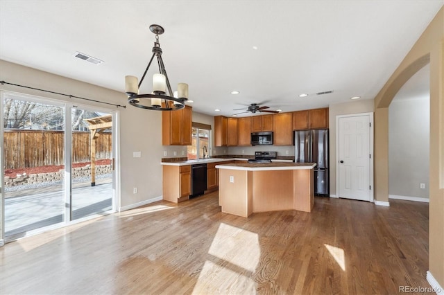 16351 E 104th Pl, Commerce City, CO 80022 - kitchen with stainless steel appliances, a chandelier, arched walkways, a center island, and light countertops