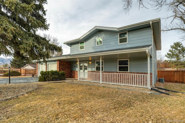 view of front of property with a front yard, central air condition unit, a porch, and a garage