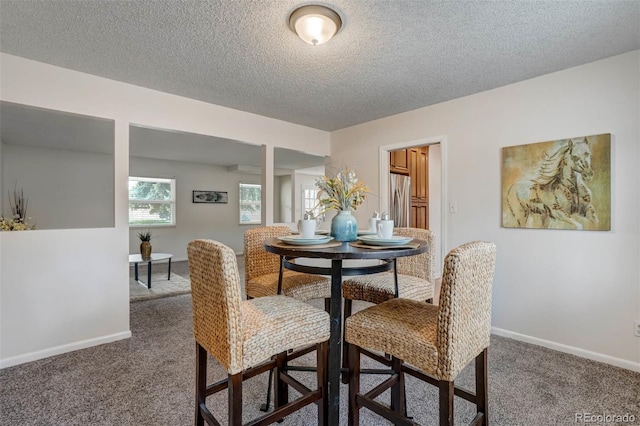 carpeted dining room featuring a textured ceiling