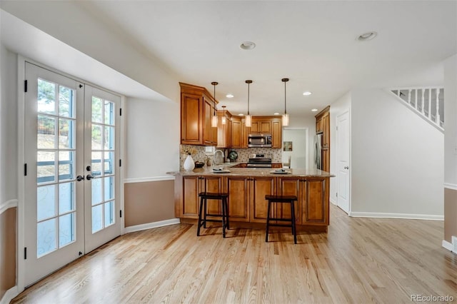 kitchen featuring stainless steel appliances, french doors, light hardwood / wood-style floors, sink, and kitchen peninsula