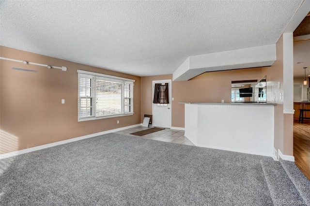 unfurnished living room featuring light carpet and a textured ceiling