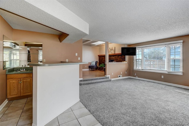 kitchen featuring light tile patterned floors, kitchen peninsula, sink, and a textured ceiling