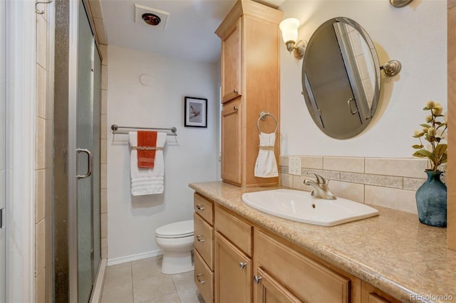 bathroom with toilet, vanity, tasteful backsplash, tile patterned floors, and a shower with door