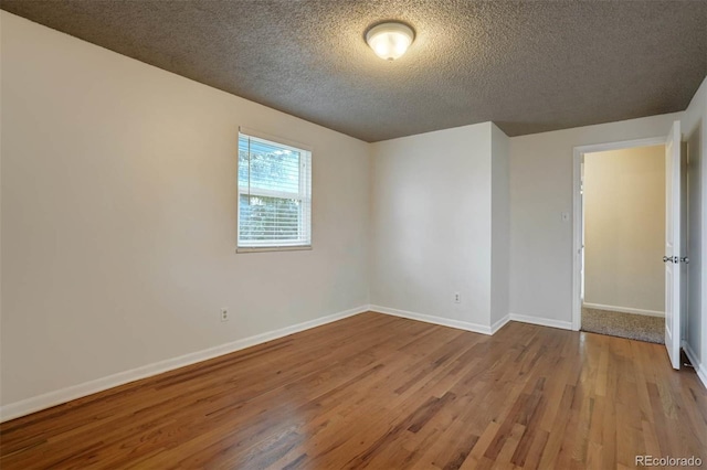 unfurnished room with a textured ceiling and light wood-type flooring