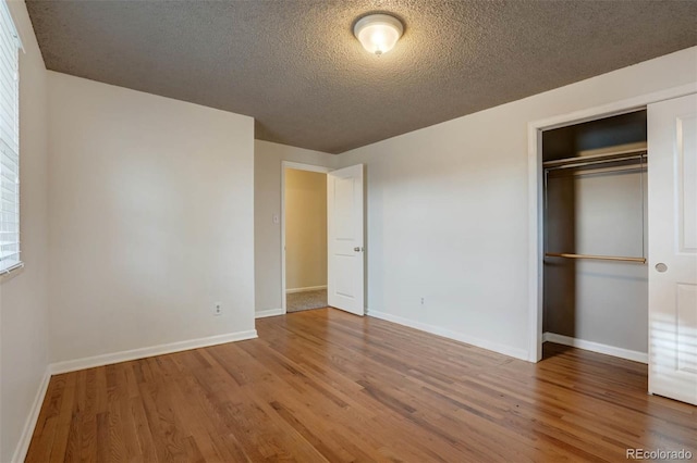 unfurnished bedroom featuring a closet, a textured ceiling, and hardwood / wood-style flooring