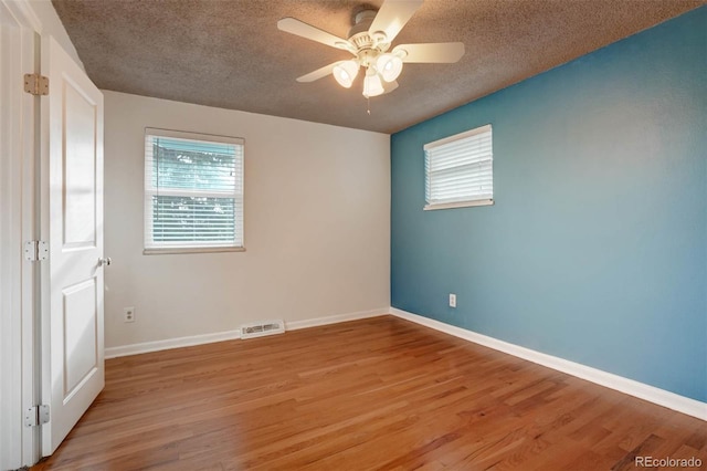 spare room with light wood-type flooring, ceiling fan, and a textured ceiling