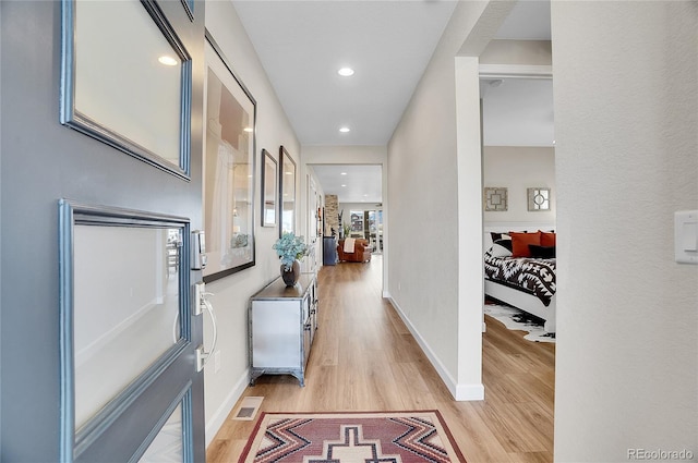 hallway with visible vents, recessed lighting, baseboards, and light wood-style floors