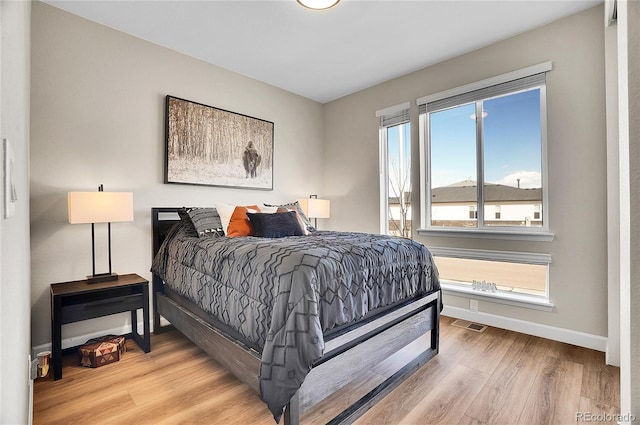 bedroom featuring visible vents, baseboards, and wood finished floors