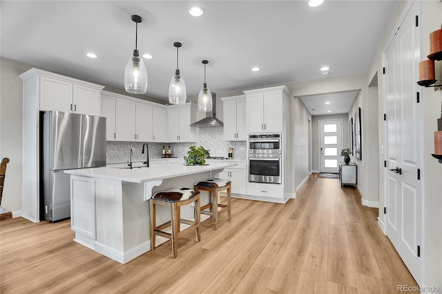 kitchen featuring white cabinetry, light countertops, wall chimney exhaust hood, and stainless steel appliances