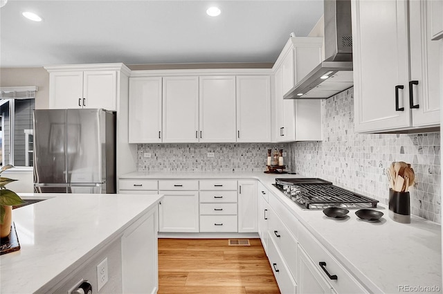 kitchen with white cabinetry, wall chimney exhaust hood, light wood-style floors, and stainless steel appliances