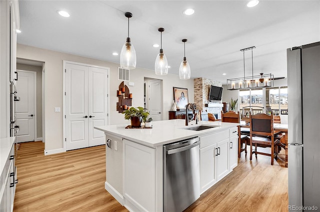 kitchen featuring a sink, stainless steel appliances, light wood finished floors, and white cabinetry