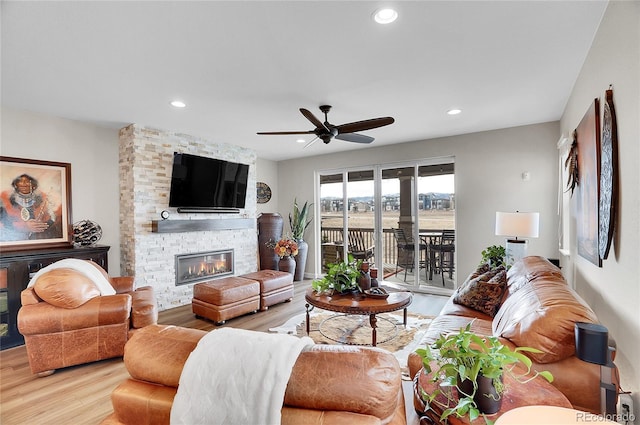 living area with recessed lighting, a fireplace, light wood-type flooring, and ceiling fan