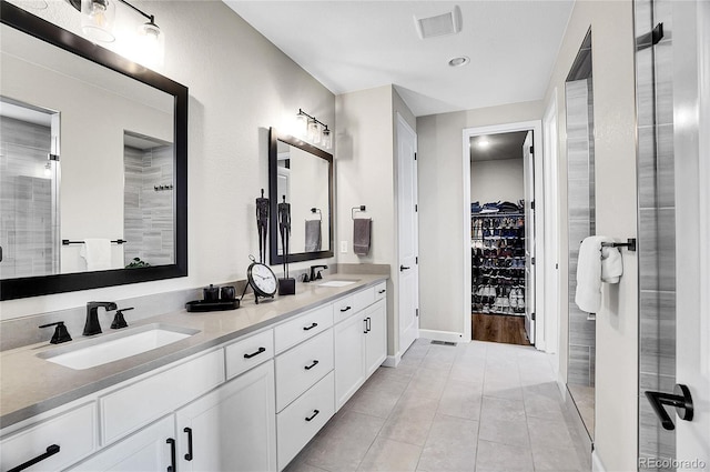 full bath featuring double vanity, a spacious closet, visible vents, and a sink