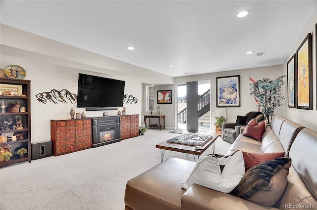 carpeted living room with recessed lighting, visible vents, a glass covered fireplace, and stairs