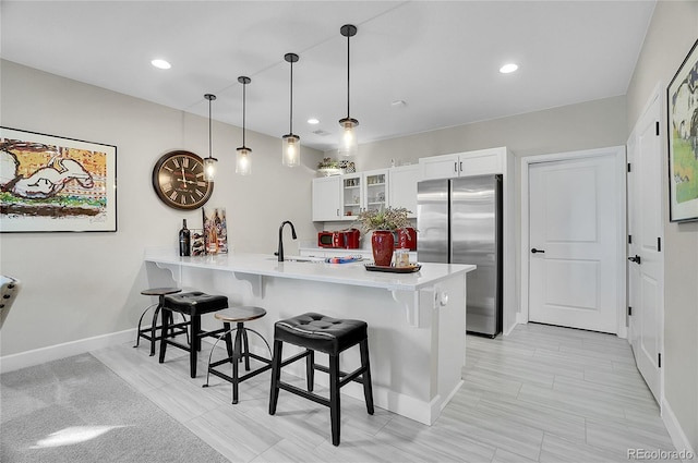 kitchen with a kitchen bar, a peninsula, glass insert cabinets, and freestanding refrigerator