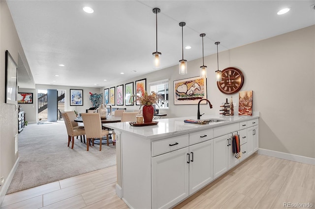 kitchen with a peninsula, recessed lighting, a sink, white cabinetry, and decorative light fixtures