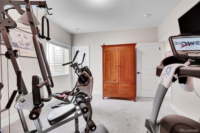 exercise area featuring light colored carpet and baseboards