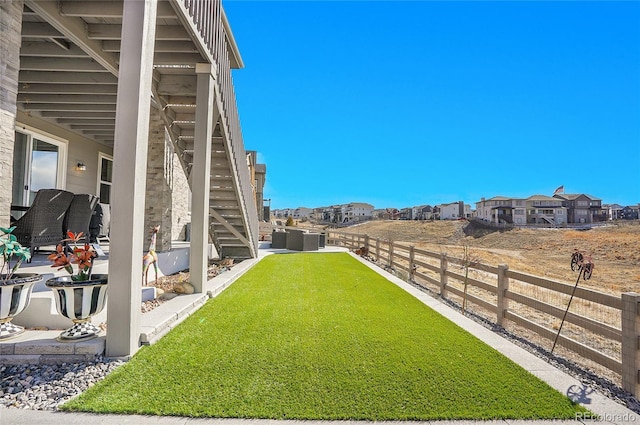 view of yard featuring stairs, a patio area, fence, and a residential view