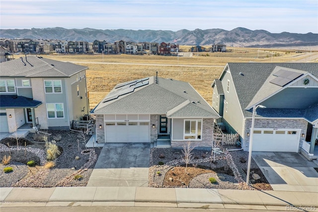 view of front facade with a residential view, a mountain view, concrete driveway, and stone siding